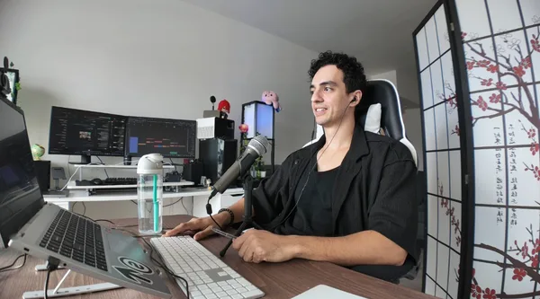 Hicham à son bureau, micro et ordinateur, souriant